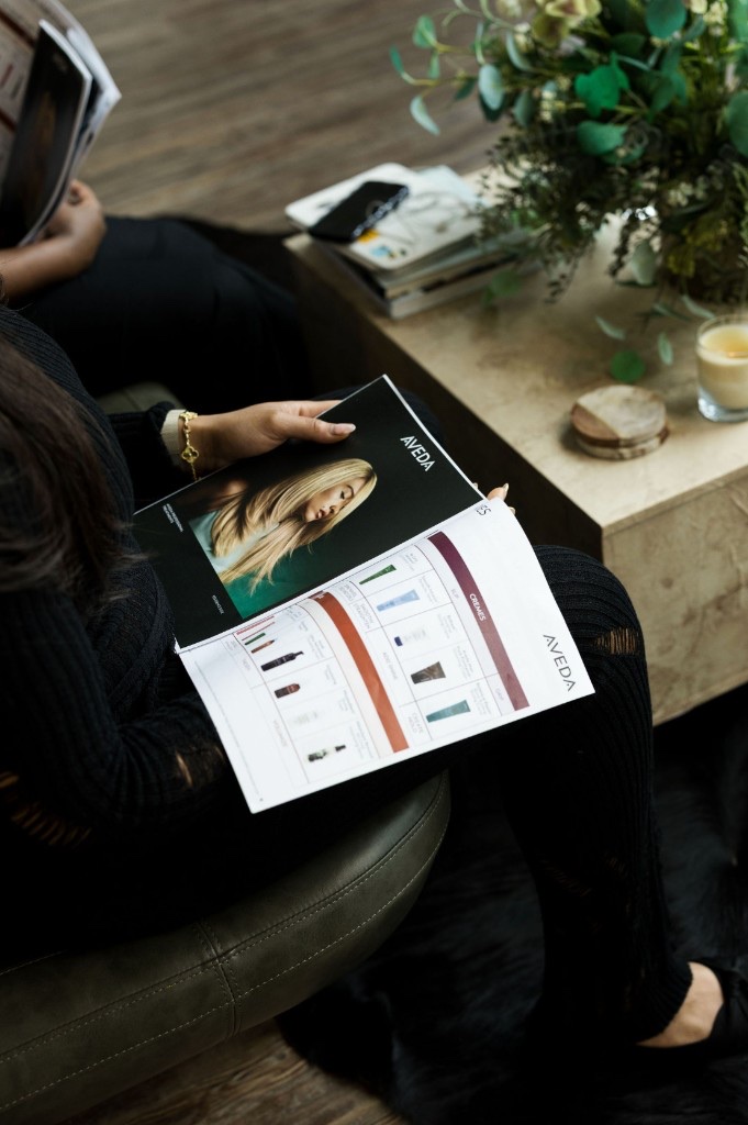 Guest browsing an Aveda product brochure at Rose Style Studio Dallas Fort Worth